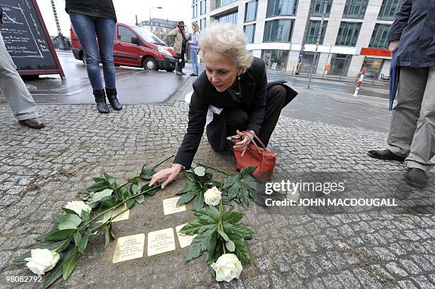 Resident Dagmar Gropper lays flowers on "stolpersteine" or stumbling stones in Berlin's Friedrichstrasse March 27, 2010. The stones, topped with...