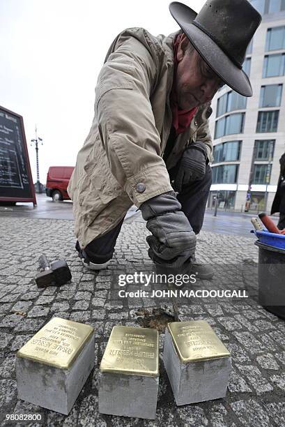 German artist Gunter Demnig digs up the pavement to lay "stolpersteine" or stumbling stones in Berlin's Friedrichstrasse March 27, 2010. The stones,...