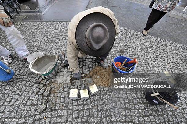 German artist Gunter Demnig lays "stolpersteine" or stumbling stones in Berlin's Friedrichstrasse March 27, 2010. The stones, topped with small brass...