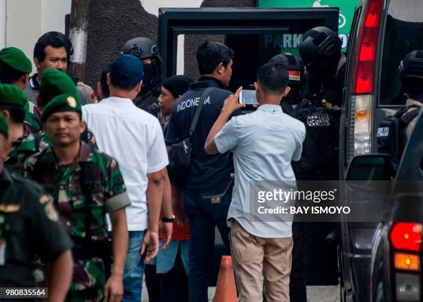 Indonesian anti-terror police officers escort Aman Abdurrahman , who is suspected of masterminding a 2016 gun and suicide attack in the capital...