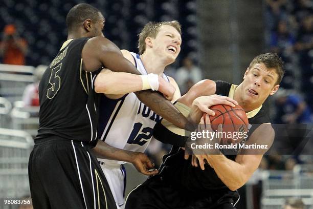 Forward Kyle Singler of the Duke Blue Devils is fouled by Keaton Grant and Chris Kramer of the Purdue Boilermakers during the south regional...