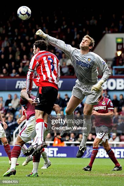 Goalkeeper Robert Green of West Ham punches the ball clear as Danny Higginbotham of Stoke closes in during the Barclays Premier League match between...