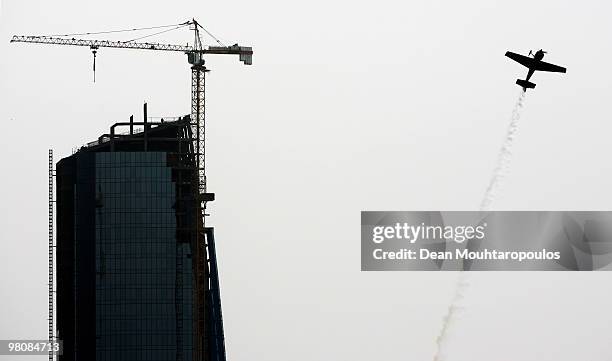 Yoshihide Muroya of Japan flys near the Etihad Towers during the Red Bull Air Race day on March 27, 2010 in Abu Dhabi, United Arab Emirates.