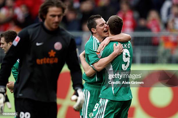 Edin Dzeko of Wolfsburg celebrates after scoring his team's first goal with team mate Marcel Schaefer as goalkeeper Heinz Mueller of Mainz reacts...