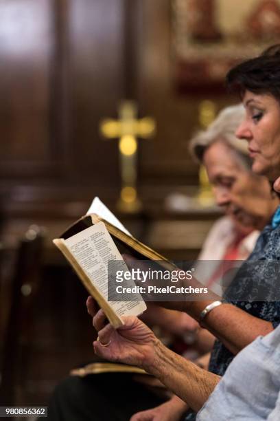 gros plan femmes occupant hymne livres en chapelle crucifix doré dans le fond - livre de cantiques photos et images de collection