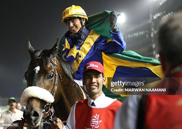 Brazilian jockey Tiago Pereira wraps his national flag around him as he celebrates after leading Gloria De Campeao to win the Dubai World Cup at the...