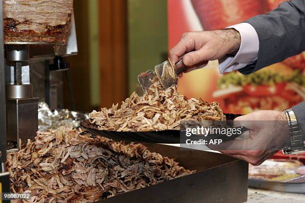 An exhibitor serves kebab meat from a new doner kebab-cutting robot during the "Doga", the doner gastronomy trade fair in Berlin on March 27, 2010....