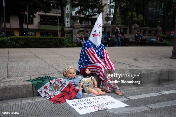 Protester wearing American flag-themed clothing sits on a sidewalk during a 'Families Belong Together' rally outside the U.S. Embassy in Mexico City,...