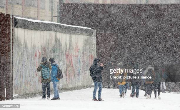 March 2018, Germany, Berlin: Young people visiting the Berlin Wall memorial under the driving snow in the Wedding district. Photo: Wolfgang Kumm/dpa