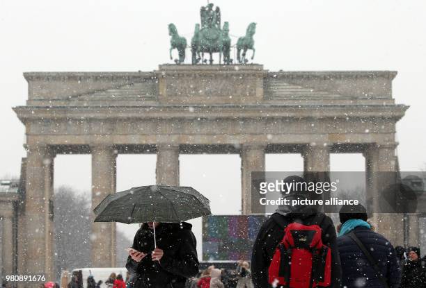 March 2018, Germany, Berlin: Tourists walking under the driving snow along the street Unter den Linden before the Brandenburg Gate. Photo: Wolfgang...