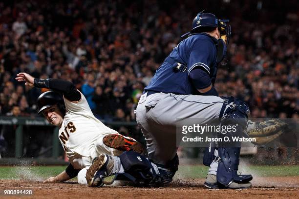 Buster Posey of the San Francisco Giants slides into home plate to score a run ahead of a tag from A.J. Ellis of the San Diego Padres during the...