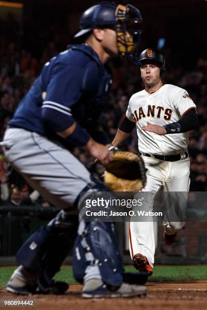 Buster Posey of the San Francisco Giants runs to home plate to score a run past A.J. Ellis of the San Diego Padres during the eighth inning at AT&T...