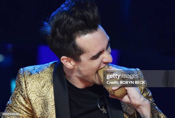Lead singer of US band Panic! At The Disco, Brendon Urie, pretends to take a bite out of a potato that was given to him as a gift, on stage at the...