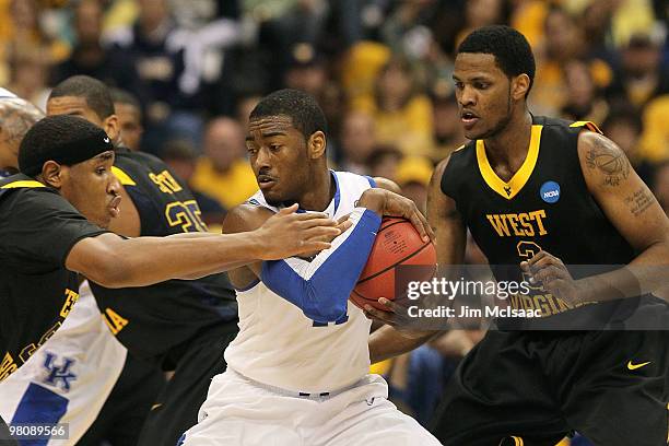 John Wall of the Kentucky Wildcats attempts to maintain control of the ball inthe first half against Kevin Jones and Devin Ebanks of the West...