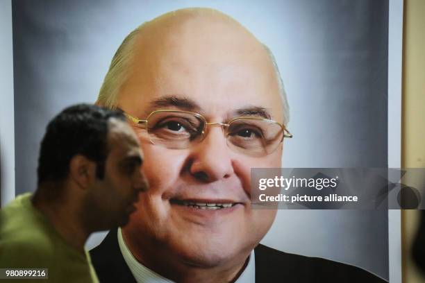 Man pases in front of a poster of Egyptian Presidential candidate and leader of El-Ghad Party Moussa Mostafa Moussa in front of the party's...