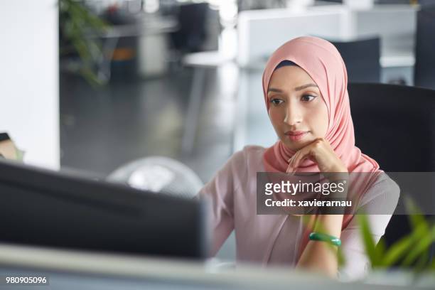 businesswoman in hijab working at computer desk - islam stock pictures, royalty-free photos & images
