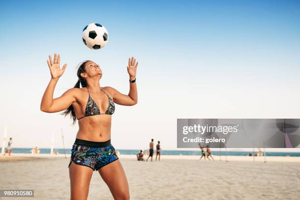 brazilian woman juggling ball on head at beach in rio de janeiro - stereotypically brazilian stock pictures, royalty-free photos & images