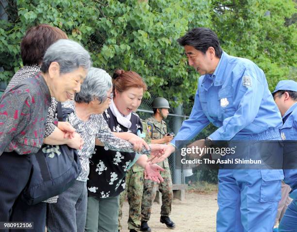 Prime Minister Shinzo Abe shakes hands with those affected by the earthquake as he inspects the damage of magnitude 6.1 strong earthquake hit area on...