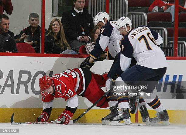 Patrick Dwyer of the Carolina Hurricanes gets taken to the ice by Chris Thorburn of the Atlanta Thrashers as they battle for the puck during their...