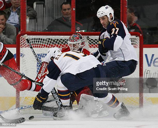 Manny Legace of the Carolina Hurricanes keeps his eye on the puck as Marty Reasoner of the Atlanta Thrashers looks to put it in the net during their...
