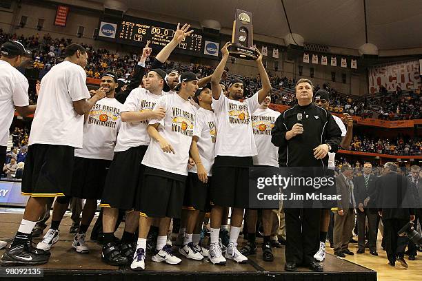 Head coach Bob Huggins of the West Virginia Mountaineers gets set to address the crowd as his playes celebrate with the East Regional trophy after...