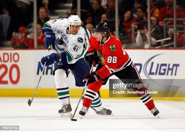 Patrick Kane of the Chicago Blackhawks looks to pass as Andrew Alberts of the Vancouver Canucks closes in at the United Center on March 5, 2010 in...