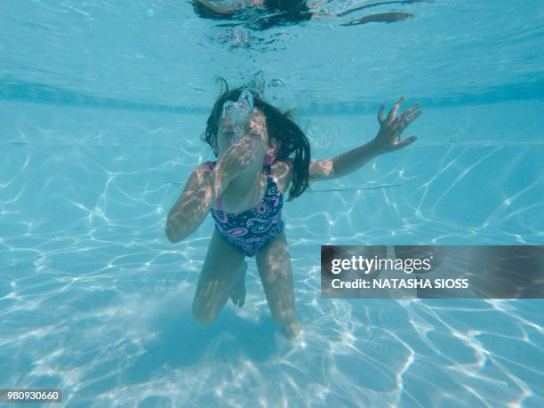 underwater photo of young girl in a swimsuit in a private pool - 鼻をつまむ ストックフォトと画像