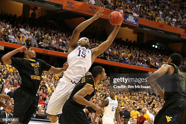 DeMarcus Cousins of the Kentucky Wildcats reaches for a rebound against Da'Sean Butler and Kevin Jones of the West Virginia Mountaineers during the...