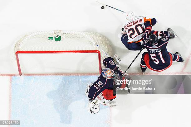 Fedor Tyutin of the Columbus Blue Jackets follows Sean Bergenheim of the New York Islanders as he skates the puck behind goaltender Mathieu Garon of...