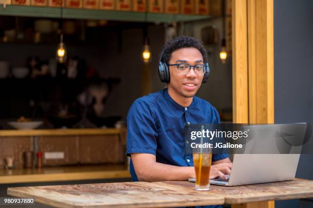 porträt eines jungen mannes mit laptop in einem café - jgalione stock-fotos und bilder