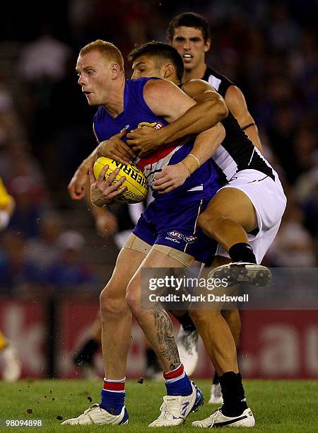 Adam Cooney of the Bulldogs is tackled by Sharrod Wellingham of the Magpies during the round one AFL match between the Western Bulldogs and the...