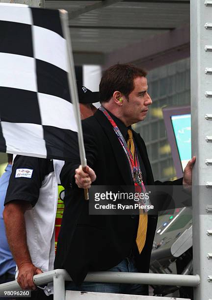 Actor John Travolta waves the chequered flag at the end of the Australian Formula One Grand Prix at the Albert Park Circuit on March 28, 2010 in...