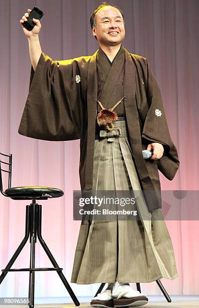 Masayoshi Son, president and chief executive officer of SoftBank Corp., dressed in a kimono, holds up the company's HTC Desire smartphone during the...