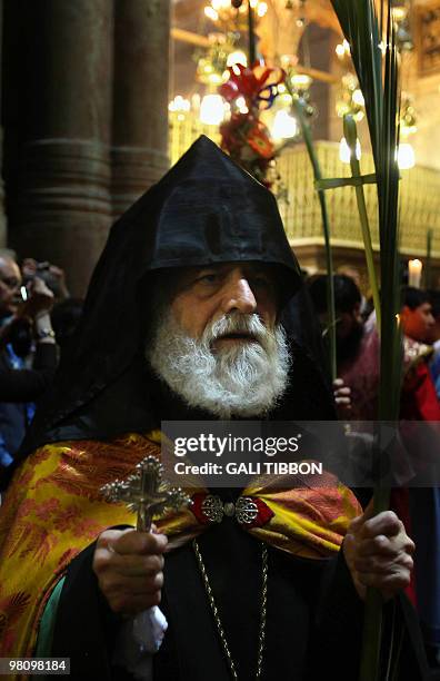 An Armenian Orthodox priest holds a cross and palm tree branches during the Palm Sunday mass at the Church of the Holy Sepulchre in Jerusalem's old...