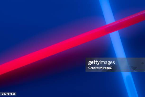 glow sticks crossing on deep blue - red x stock pictures, royalty-free photos & images