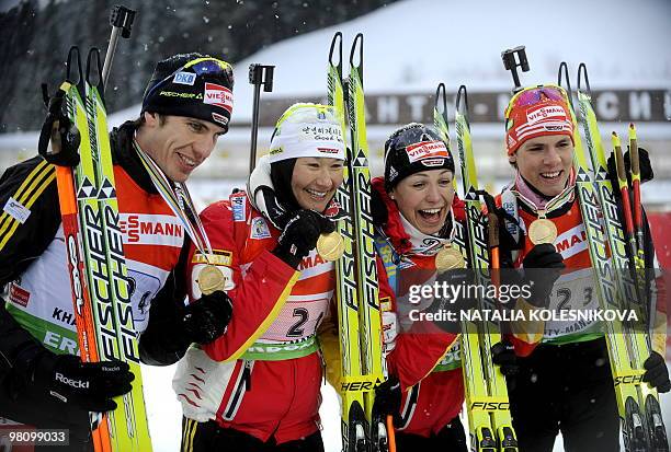 Germany's Arnd Peiffer, Simone Hauswald, Magdalena Neuner and Simon Schempp celebrate with their gold medals their first place on the podium after...