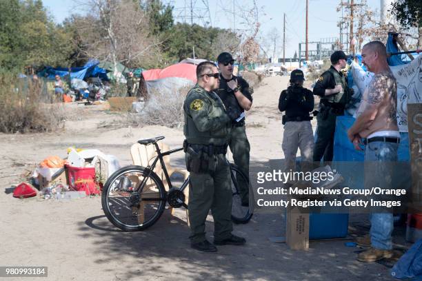 Orange County Sheriff's Deputies talk to a homeless man along Santa Ana River Trail in Anaheim, California on Monday, Jan. 29, 2018.