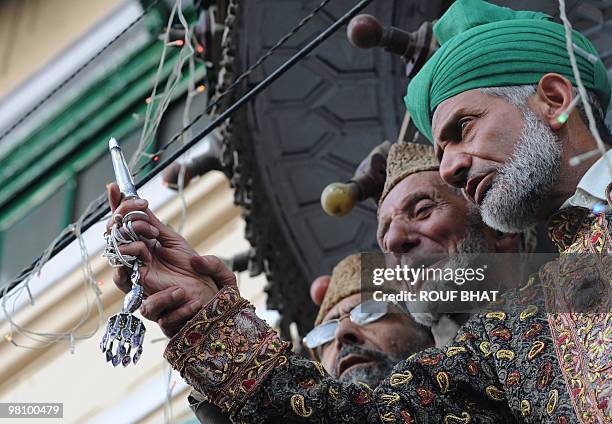 Unseen Kashmiri Muslim men praying at a shrine to Saint Syed Abdul Qadir Jilani react as the head imam shows a believed relic of the Sufi saint on...