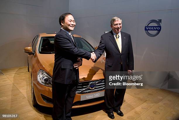Li Shufu, chairman of Zhejiang Geely Holding Co., left, and Lewis Booth, chief financial officer at Ford Motor Co., shake hands at the start of a...