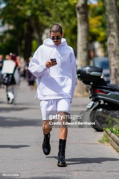 Guest wears a white hoodie sweater, white shorts, black shoes, outside Rick Owens, during Paris Fashion Week - Menswear Spring-Summer 2019, on June...
