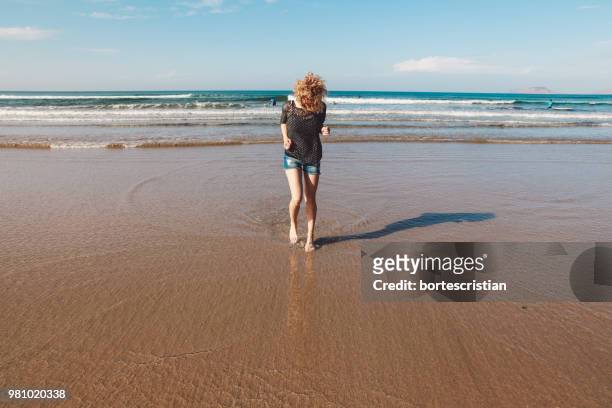 young woman walking at beach - bortes stockfoto's en -beelden