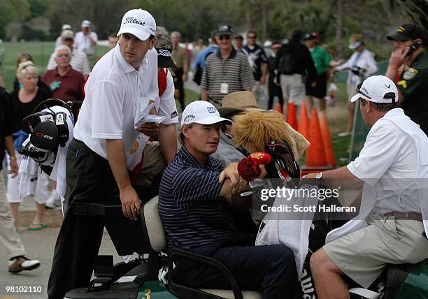 Ernie Els of South Africa rides with Ben Curtis and their caddies off the 14th hole after play was suspended for dangerous weather during the final...