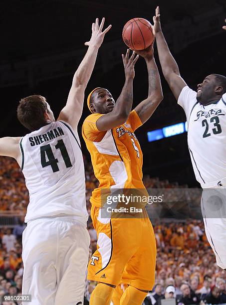 Wayne Chism of the Tennessee Volunteers tries to shoot through Garrick Sherman and Draymond Green of the Michigan State Spartans during the midwest...