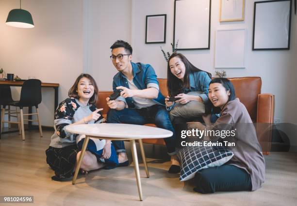 4 aziatische chinese vrienden spel van tv in de woonkamer - game four stockfoto's en -beelden