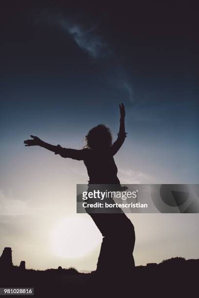 low angle view of silhouette woman dancing against sky during sunset - bortes stock-fotos und bilder