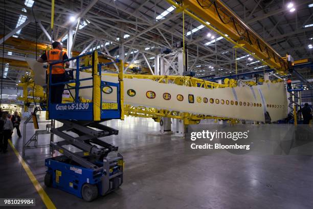 An employee works on the Airbus A350 wing assembly production line while standing in a scissor lift at the Airbus SE factory in Broughton, U.K., on...