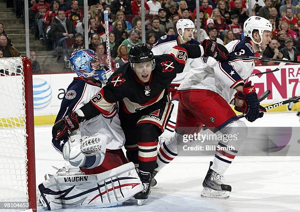 Kris Versteeg of the Chicago Blackhawks pushes through goalie Steve Mason and Marc Methot of the Columbus Blue Jackets on March 28, 2010 at the...