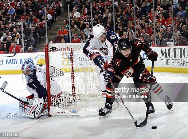 Kris Versteeg of the Chicago Blackhawks and Rick Nash of the Columbus Blue Jackets fight for the puck as Jackets goalie Steve Mason watches from in...