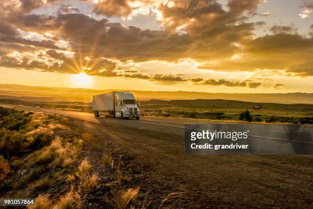 semi-vrachtwagen op een interstate highway in de schemering met cloudscape - vrachtwagen banden stockfoto's en -beelden