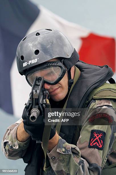 French marine petty officer Loic Berlan-Landrin makes a demonstration with his FAMAS assault rifles on March 22 on the deck of French...